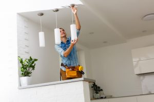 An electrician installing and connecting a lamp to the ceiling
