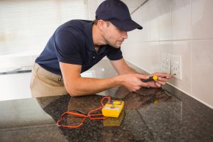 An electrician unscrewing the face plate