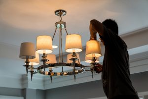An Electrician changing the bulbs of a chandelier