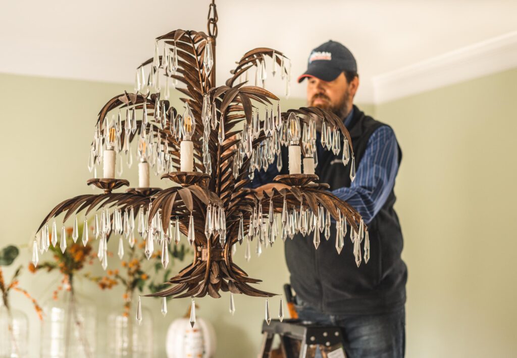Technician finishes the installation of a chandelier with the last crystals being added