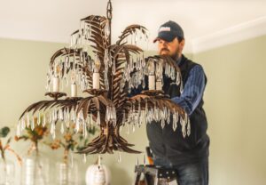 Technician finishes the installation of a chandelier with the last crystals being added