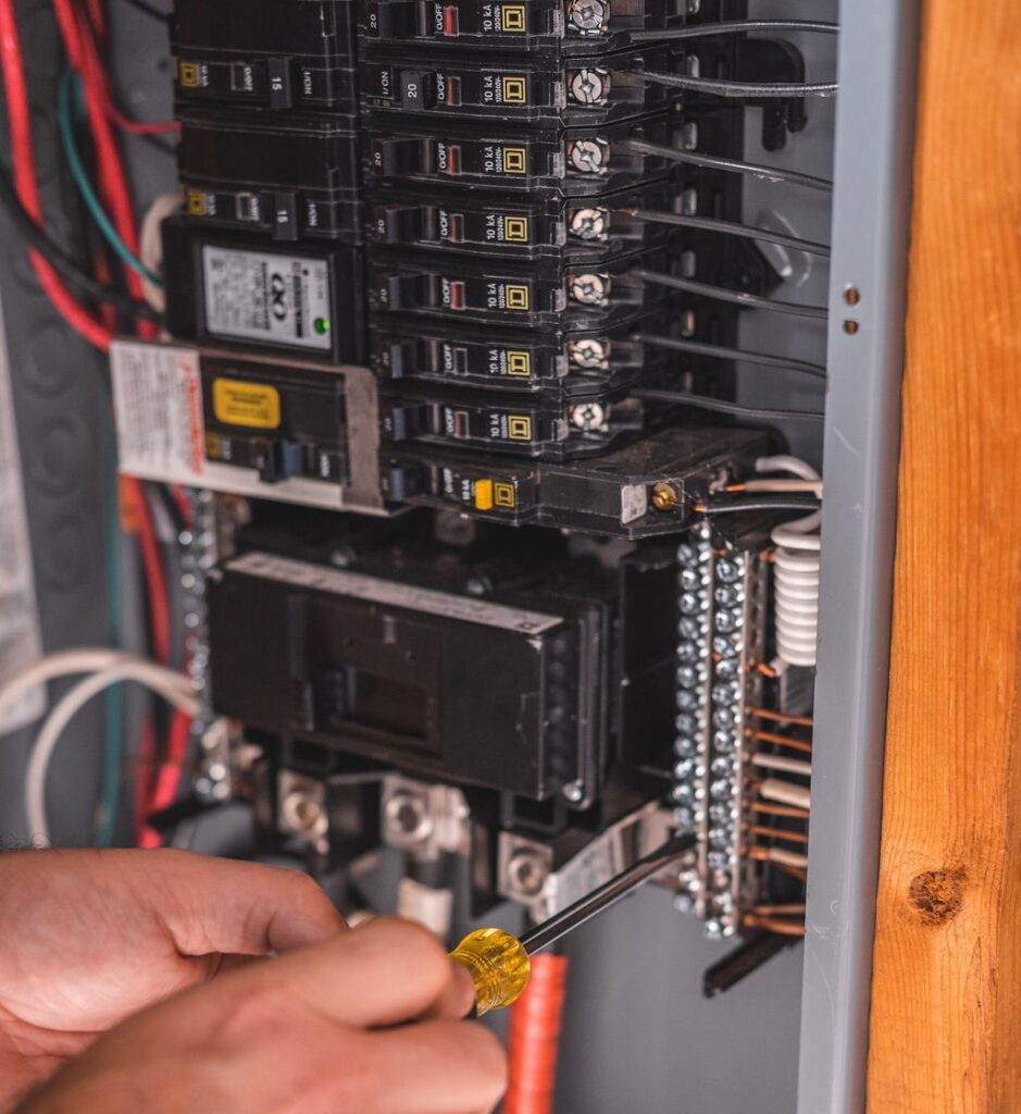 Technician tightens the screws in the electrical panel during an electrical inspection